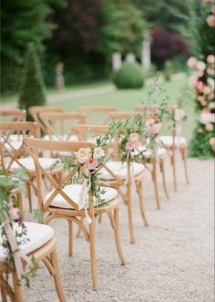 rows of chairs with flowers on them in the middle of an outdoor ceremony aisle lined with pink roses and greenery