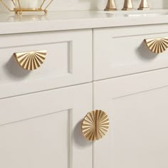 a white cabinet with gold handles and knobs on the front, along with other cabinets