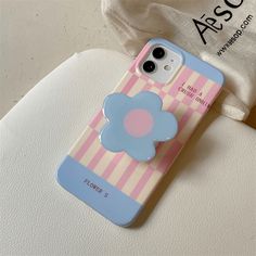 an iphone case with a flower on it sitting on top of a white chair next to a bag