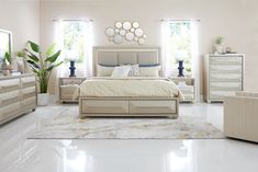 a bedroom with white walls and flooring has a bed, dressers, chair, mirror and two windows