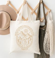 a white tote bag hanging on a wall next to two hats and other items