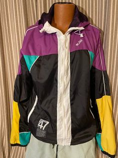 This great polyester windbreaker jacket is made by Lifted Research Group in a size XL.  It is a mix of black, yellow, purple, jade and white, with zippered pockets, and hood.  Lined in black mesh.  Like new condition.  As is, no returns. Sporty Windbreaker With Double-lined Hood, Sports Windbreaker With Double-lined Hood, Sporty Multicolor Patchwork Windbreaker, Nylon Windbreaker With Double-lined Hood, Sportswear Nylon Windbreaker With Double-lined Hood, Black Mesh, Windbreaker Jacket, Sport Fitness, Like New