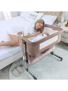 a woman laying in bed next to a baby crib