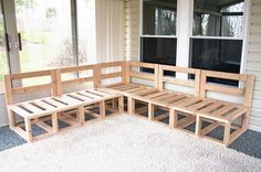 a wooden bench sitting in front of a window on top of a white fluffy rug