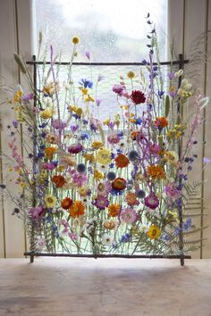 an arrangement of wildflowers in front of a window