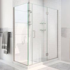 a white tiled bathroom with glass shower doors