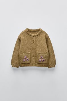 a brown cardigan sweater with pink flowers on the chest