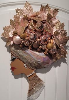 a woman's head is adorned with gold and pink ornaments, including pine cones