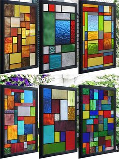 four different colored stained glass panels hanging on the side of a building with flowers in front of them