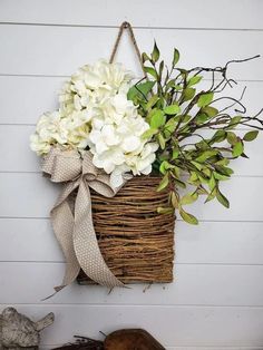 a basket filled with white flowers hanging on a wall next to a stuffed animal and wooden planks