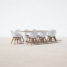 a group of white chairs sitting around a wooden table