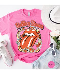 Step back in time and rock out in style with our Vintage Flower Rolling Stone Tee! 🌸🎸 This retro-inspired t-shirt features a classic Rolling Stone logo beautifully intertwined with vibrant flowers, capturing the free-spirited essence of rock 'n' roll and the timeless charm of the 70s. 🌼✨ Crafted from super-soft, high-quality fabric, this tee offers ultimate comfort and a perfect fit, making it an essential addition to your wardrobe. Whether you're heading to a concert, a festival, or just channeling your inner rock star, this tee will have you looking effortlessly cool and totally groovy. 🌟👕 Get ready to roll and bloom with style! 🌿🎶🛒 Retro Pink Printed T-shirt, Spring Festival Hippie T-shirt, Spring Festival Casual T-shirt, Trendy Festival T-shirt With Graphic Print, Retro Relaxed Fit T-shirt For Music Festival, Hippie Multicolor T-shirt For Spring, Retro Festival T-shirt With Screen Print, Vintage Summer Fan Merchandise Tops, Vintage Summer Tops For Fan Merchandise