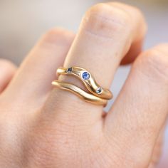 a woman's hand holding a gold ring with two blue sapphire stones on it