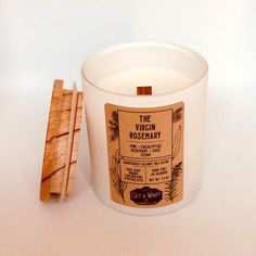 a candle and wooden coaster on a white surface with the label virginia rosemary next to it