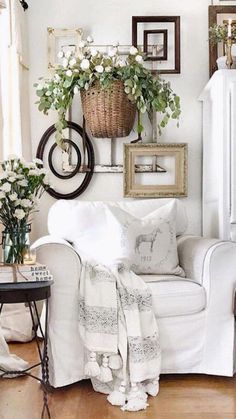 a living room with white furniture and flowers in vases on the wall above it