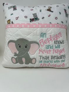 an elephant pillow is shown on a white surface with pink and green trimmings