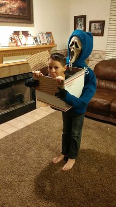 a young boy in a costume holding a box