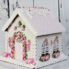 a small white house with pink decorations on the roof and windows, decorated with pearls