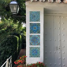 a white building with blue and green tiles on the wall next to potted plants