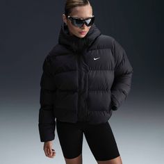 Up your outerwear game in this insulated puffer jacket. A loose fit makes it ideal for layering while the Nike Therma-FIT technology helps manage your body’s natural heat to help keep you warm in cold-weather conditions. A water-repellent finish, bungees at the hem and a hood work together to help shield you from wind and rain. Fit & Design: Warm, hip-length jacket with loose fit Designed to avoid clumping, the fill maintains a smooth layer of insulation—even after being washed Water-repellent finish on sturdy ripstop fabric helps keep you dry in wet weather Construction: Synthetic insulation Storage: Hand pockets and interior pocket Trim: Hood and elongated neck coverage Elongated bungee toggles at hood Full-length zipper Snap closure Embroidered Swoosh logo Therma-FIT embroidery Winter Coat Black, Womens Athletic Outfits, Black Winter Coat, Women's Sportswear, Wind And Rain, Ripstop Fabric, Swoosh Logo, Women Lifestyle, Wet Weather