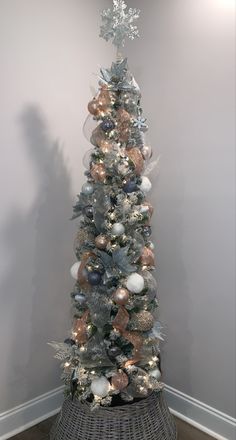 a white christmas tree with silver and gold ornaments in a wicker basket on the floor