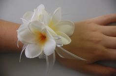 a person's hand holding a white flower on their wrist with a ribbon around it