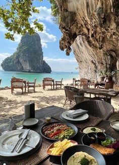 an outdoor dining area on the beach with chairs and tables set up for two people