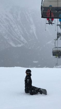 a person sitting in the snow under a ski lift