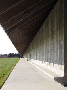 an empty walkway between two large concrete pillars in the middle of a grassy area with trees on either side