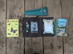 the contents of an outdoor survival kit laid out on a wooden table next to a book