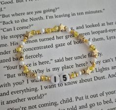 a bracelet with yellow and white beads on top of an open page of a book