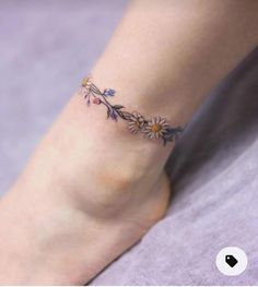 a woman's foot with a small flower tattoo on her left ankle and the bottom part of her leg