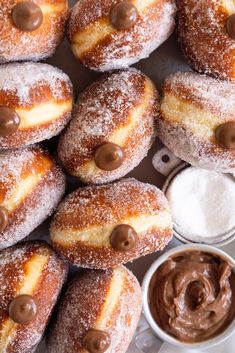 powdered sugar and chocolate donuts are arranged on a plate with dipping sauces