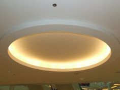 a circular light fixture in the middle of a room with white walls and ceiling lights