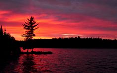 the sun is setting over some water and trees