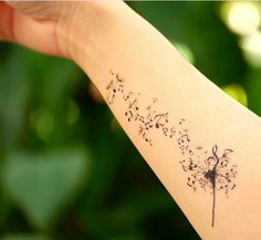 a person's arm with a dandelion tattoo on it