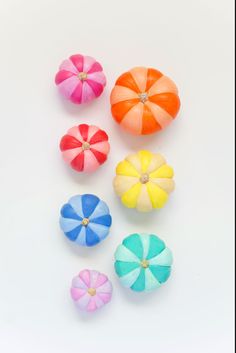 four different colored umbrellas sitting next to each other on a white surface with no one around them