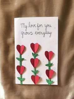 a card with paper hearts attached to the back of it and two green stems on each side