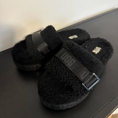 Ugg Fluffita Slide Black Black Leather Winter Slippers, Black Cozy Slippers With Round Toe, Black Flat Slippers With Textured Footbed, Cozy Black Slip-on Slippers, Black Slippers With Textured Footbed And Round Toe, Black Synthetic Slippers With Faux Fur Lining, Black Slippers With Faux Fur Lining, Black Fluffy Slippers For Winter, Black Winter Slippers With Round Toe