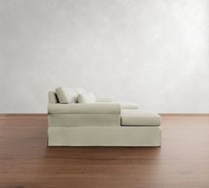 a couch sitting on top of a wooden floor next to a white wall with pillows