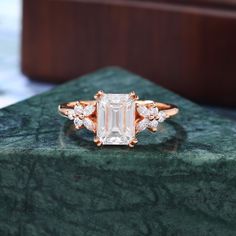 an emerald colored diamond ring on top of a green marble slab