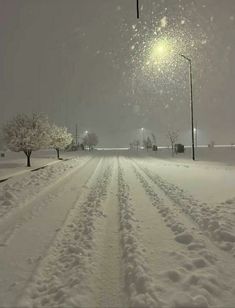 a snow covered road with street lights in the distance