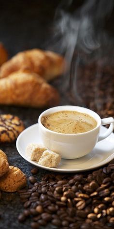 a cup of coffee sitting on top of a white saucer next to some cookies