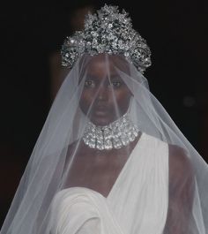 a woman wearing a veil and tiara on the runway