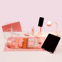 the contents of a makeup set on a pink mat with a lamp and other items