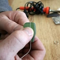 a person is working on something with scissors and wires in the background, while another hand holds an electrical wire