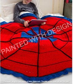 a young boy sitting on top of a bed covered in a spiderman crochet blanket