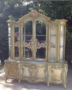 an antique china cabinet with glass doors and ornate carvings on the front, painted gold