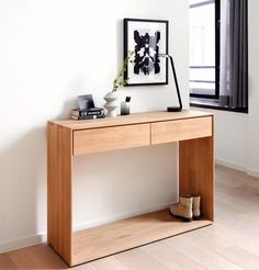 a wooden desk with shoes on it in front of a window and a framed photograph