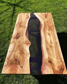 a wooden table with water in it on the grass next to some green grass and trees